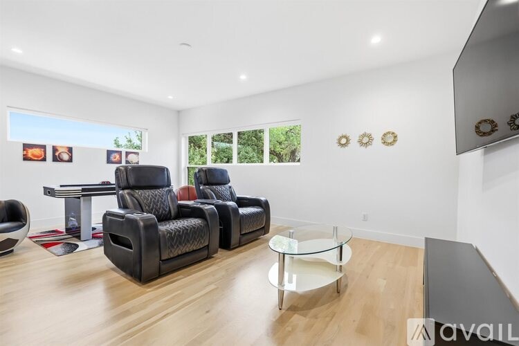 A living room with a black leather chair and a glass coffee table.