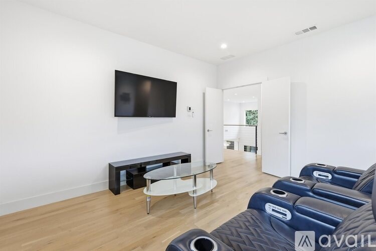 A living room with a black television and a glass coffee table.