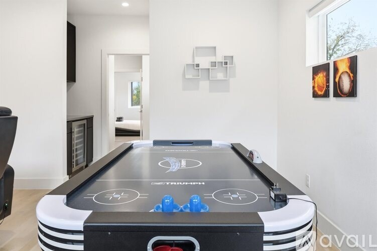 A pool table with a black cloth and blue pool balls is in the center of the room.
