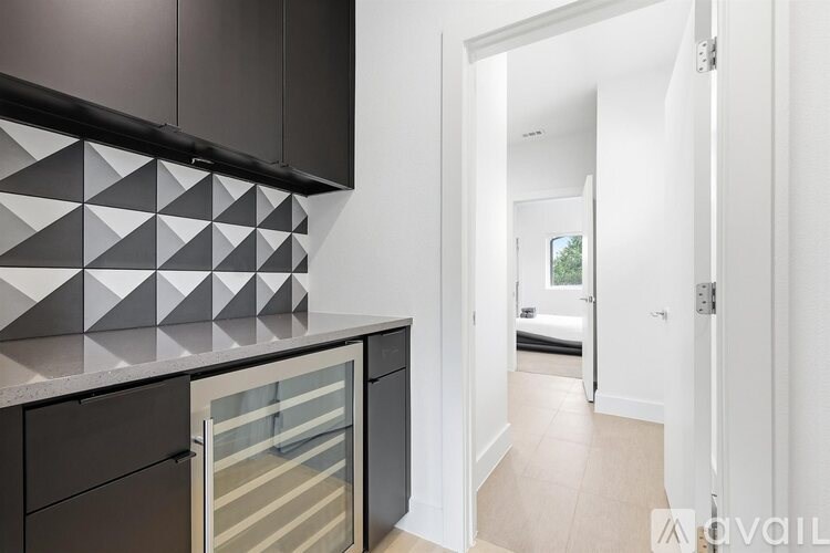 A kitchen with black cabinets and a white wall with a geometric pattern.