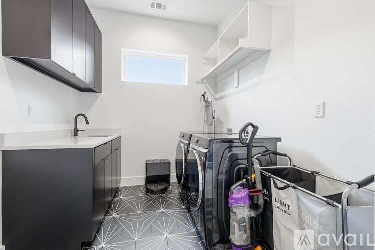 A laundry room with a washer and dryer, a sink, and a window.