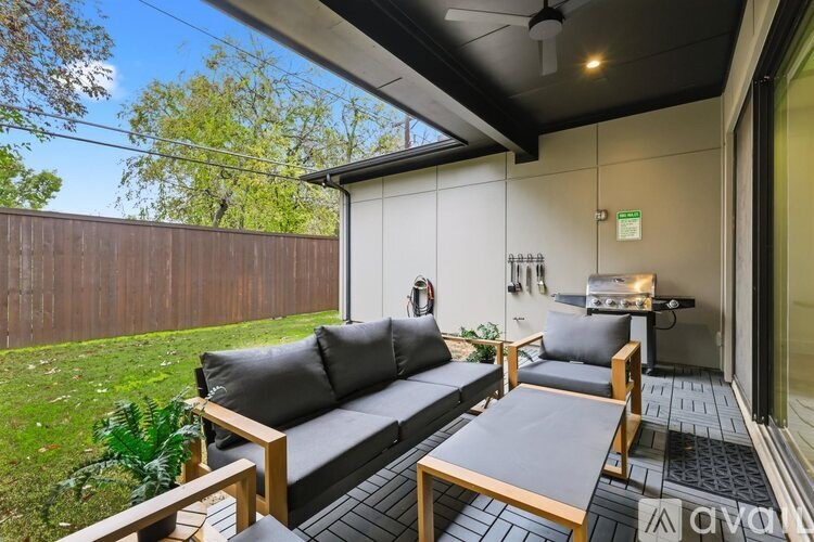 A patio with a grey couch and wooden table.
