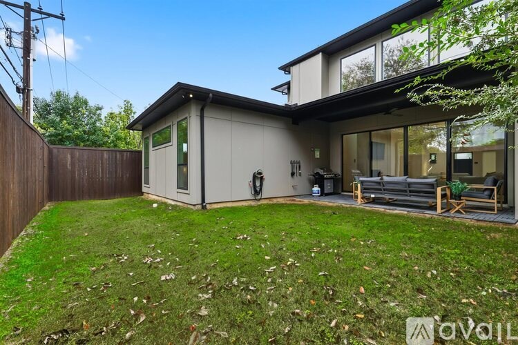 A modern house with a backyard and a wooden fence.