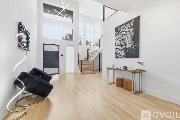 A modern living room with a black chair and a large painting of a leopard.