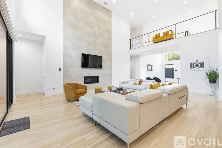 A modern living room with a large white sofa and a television on the wall.