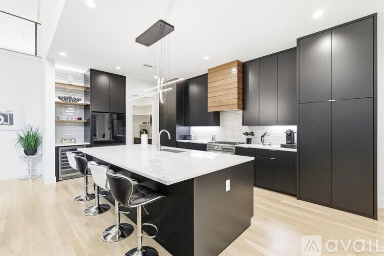 A modern kitchen with black cabinets and a white island.