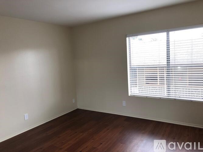A room with wooden floors and a window with blinds.