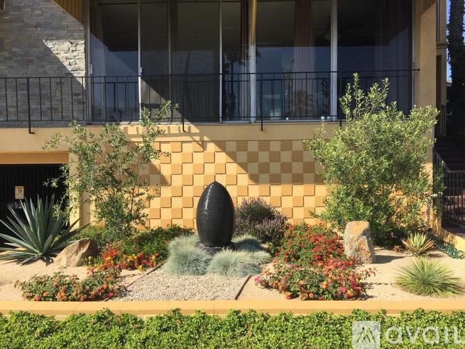 A garden with a variety of plants and a black egg-shaped object in the center.