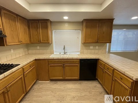 A kitchen with wooden cabinets and a black dishwasher.