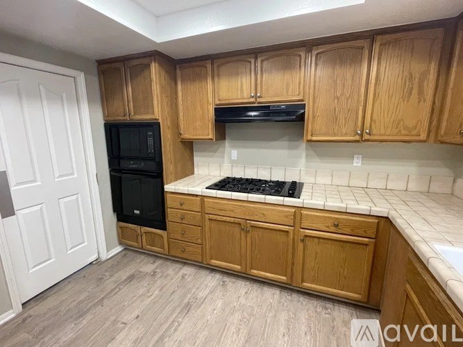 A kitchen with wooden cabinets and a black oven.