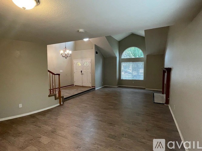 A spacious room with wooden flooring and a chandelier.