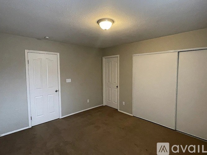 A room with a white door and a brown floor.