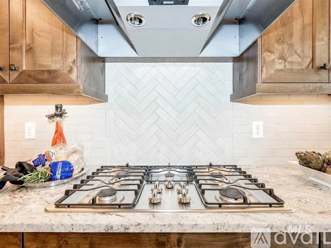 A kitchen with a stove top oven and wooden cabinets.