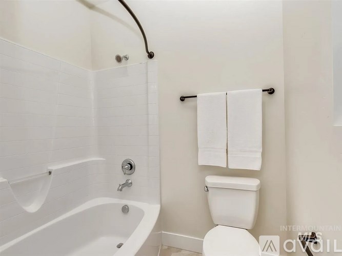 A white bathroom with a toilet, tub, and towel rack.