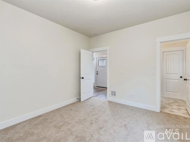 A spacious room with a carpeted floor and two doors, one of which is open.