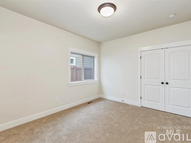 A room with a carpeted floor, a window with white blinds, and a white door.