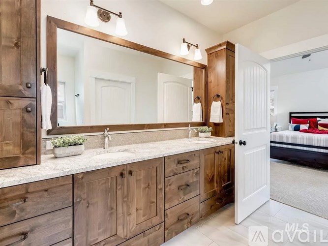 A bathroom with a large mirror and wooden cabinets.