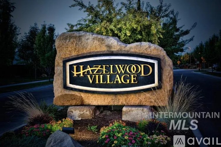 A sign that says Hazelwood Village stands in front of a dark sky.