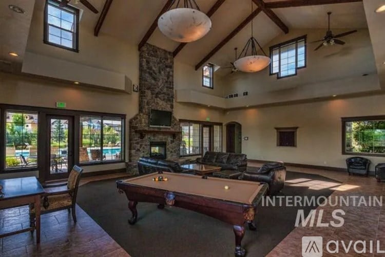A billiard table is in the middle of a room with a stone pillar and a fireplace.