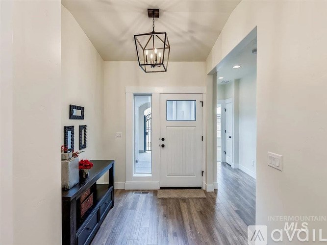 A hallway with a white door and a black chandelier.
