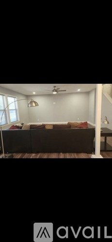 A modern living room with a black sofa and a white ceiling fan.