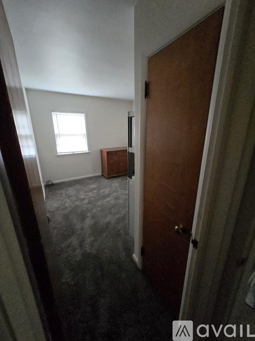 A room with a brown door and a grey carpet.