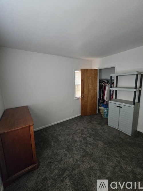A room with a grey carpet and a wooden cabinet.