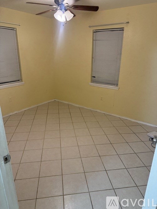 A room with a ceiling fan and two windows.