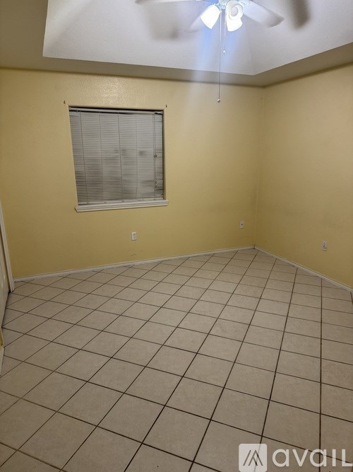 A room with a ceiling fan and a window with blinds.