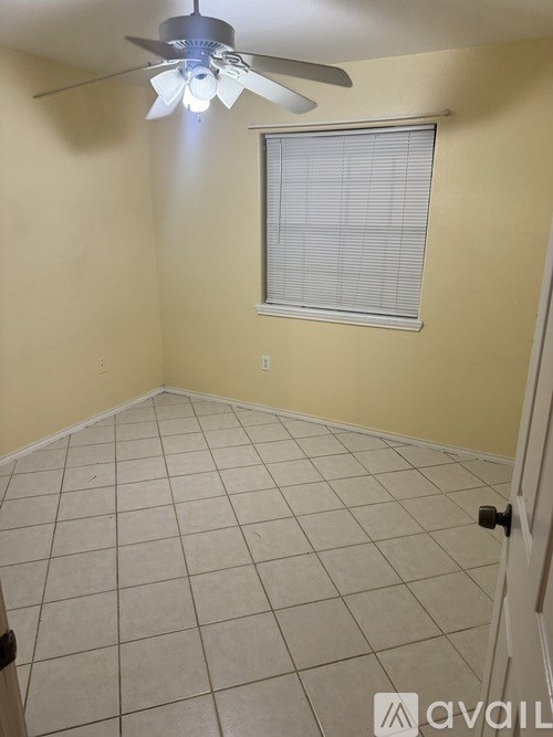A room with a ceiling fan and a window with blinds.