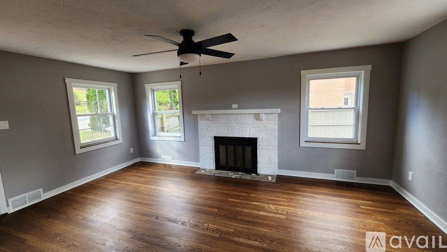 A living room with a fireplace and a ceiling fan.
