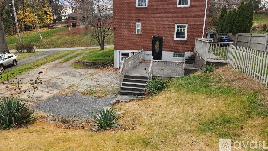 A house with a red brick exterior and a black door is surrounded by a white fence.
