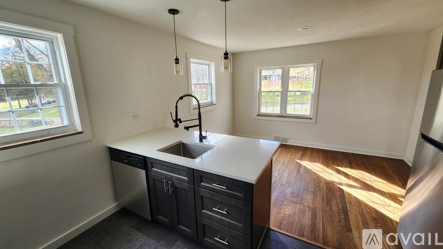 A kitchen with a sink, a window, and a wooden floor.