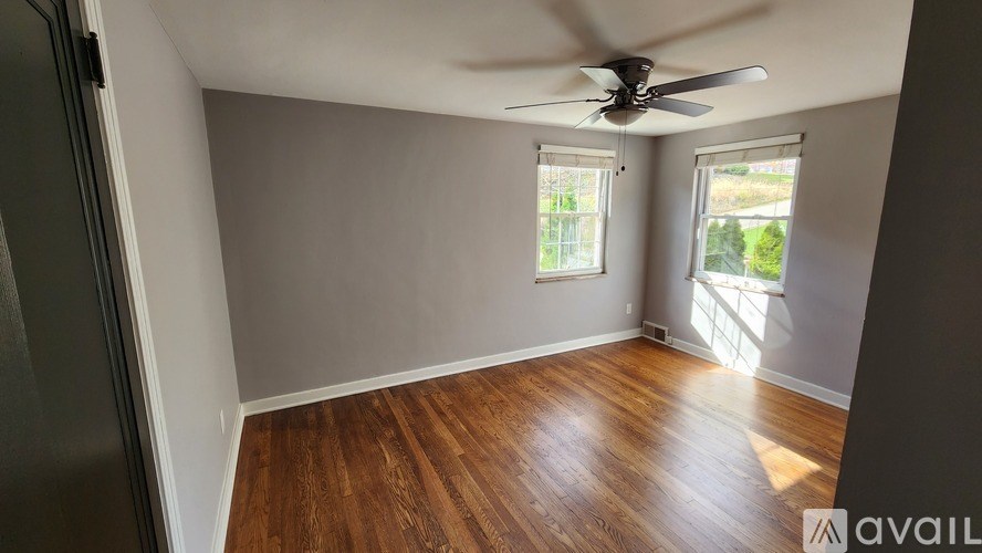 A room with wooden flooring and a ceiling fan.