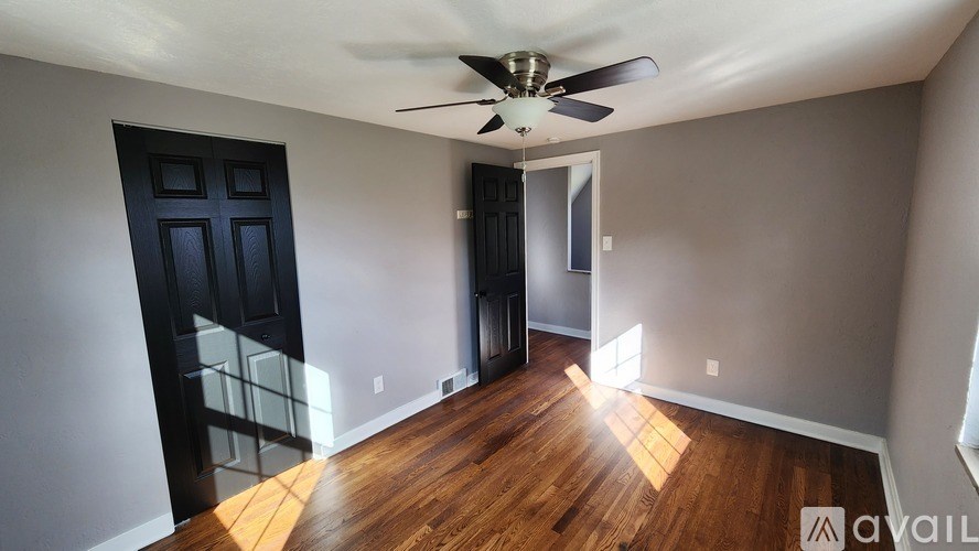 A room with a ceiling fan and wooden floors.