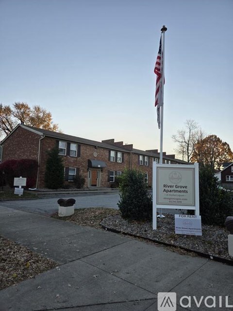 A sign for River Grove Apartments is in front of a brick building.