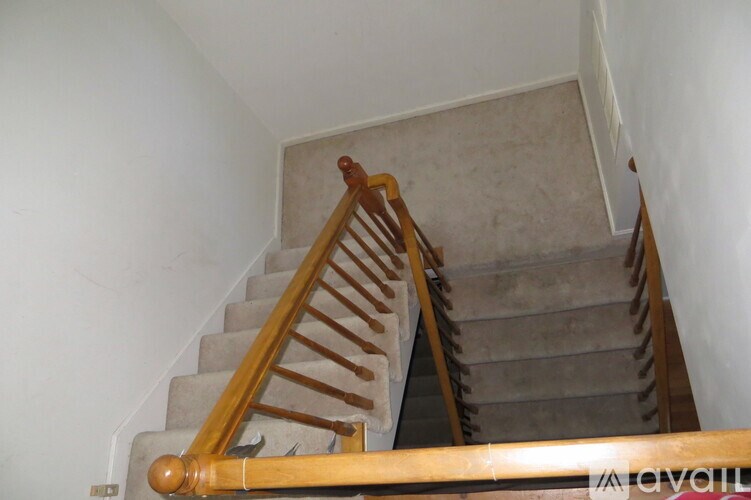 A wooden staircase with a beige carpeted runner.
