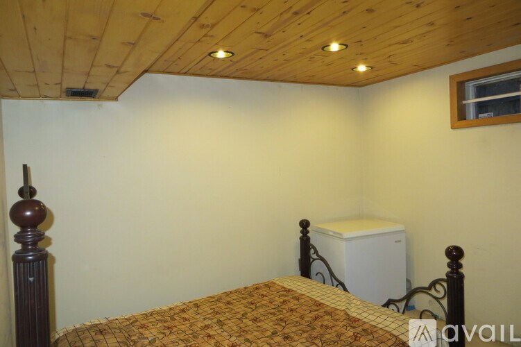 A bedroom with a bed, dresser, and window.