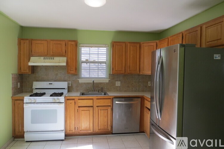 A kitchen with green walls and wooden cabinets.