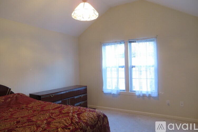 A bedroom with a bed, dresser, and window.