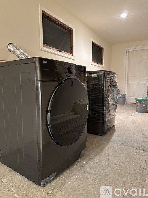 Two black washing machines in a laundry room.