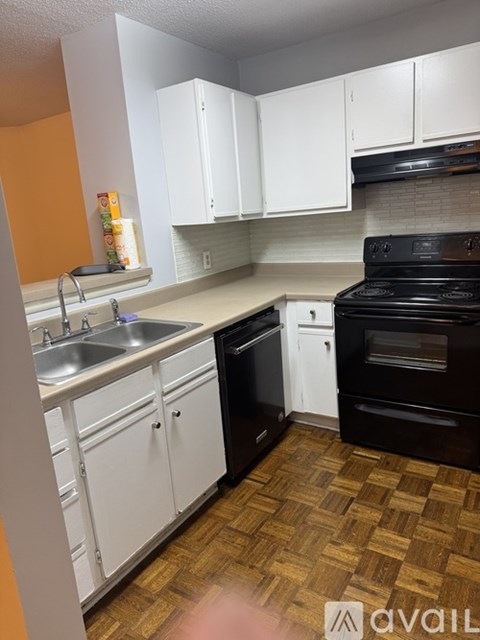 A kitchen with white cabinets and a black stove top oven.