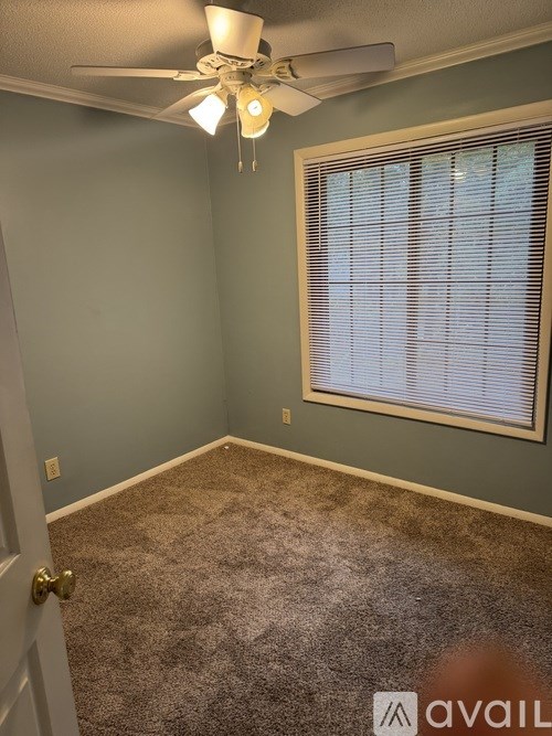 A room with a ceiling fan and a window with blinds.