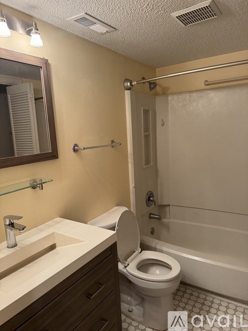 A bathroom with a toilet, sink, mirror, and bathtub.