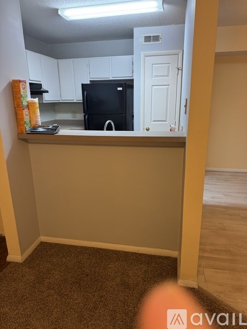A kitchen area with a black fridge and white cabinets.