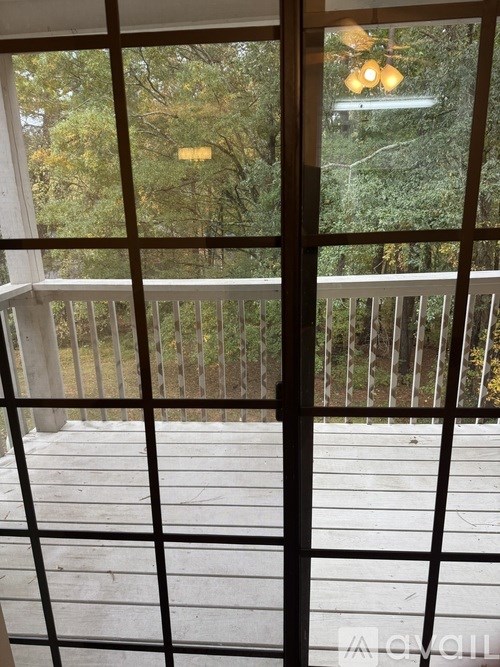 A view of a deck through a window with a tree in the background.