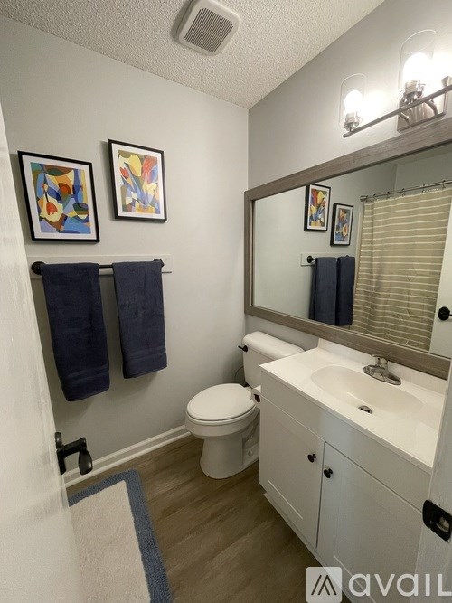 A bathroom with a toilet, sink, and two towels hanging on the wall.