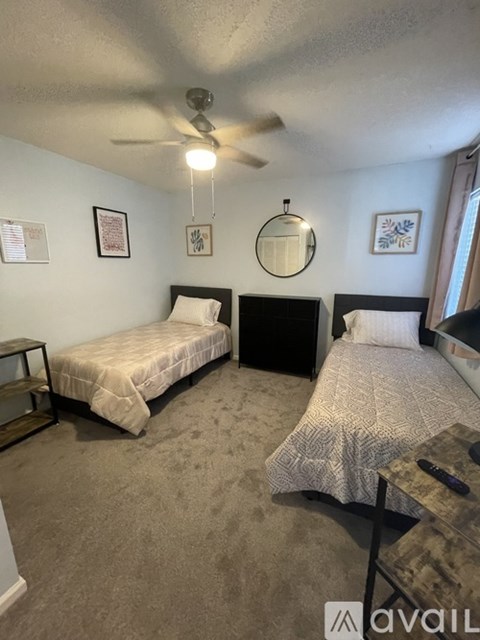 A bedroom with two beds and a ceiling fan.