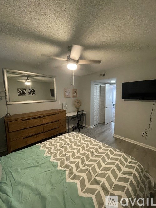 A bedroom with a bed, dresser, mirror, and a ceiling fan.