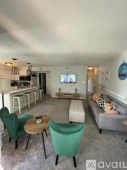 A living room with a grey couch, green chairs, and a wooden coffee table.
